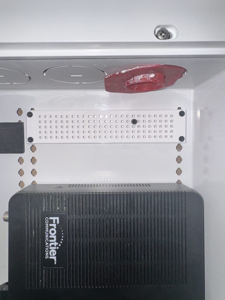 Bracket mounted at the top of the network cabinet with the device sitting below it, ready to hang