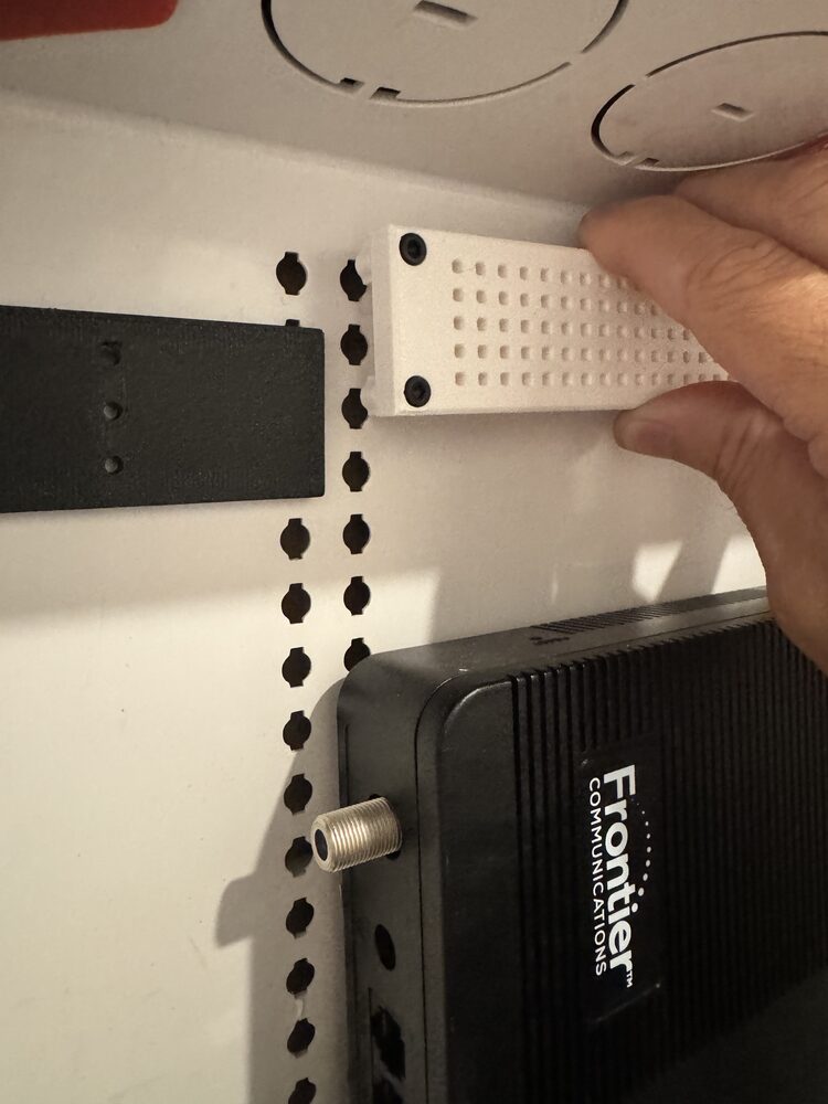 Bracket grid face with screws set in the corners, held against the cabinet's keyhole column