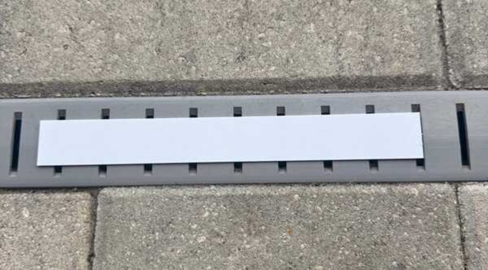 White cutting template laid flat on top of the gray drain channel